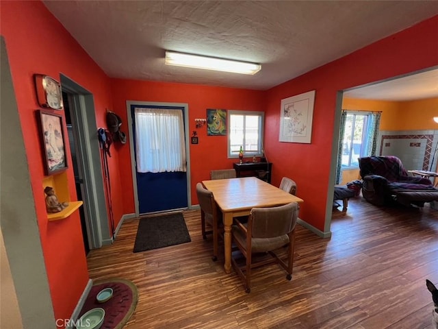 dining room with a textured ceiling, wood finished floors, a wealth of natural light, and baseboards