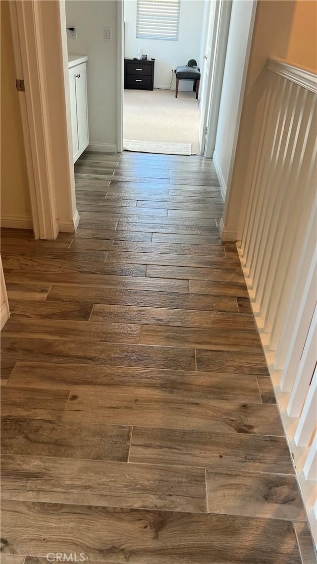 corridor with dark wood finished floors and baseboards