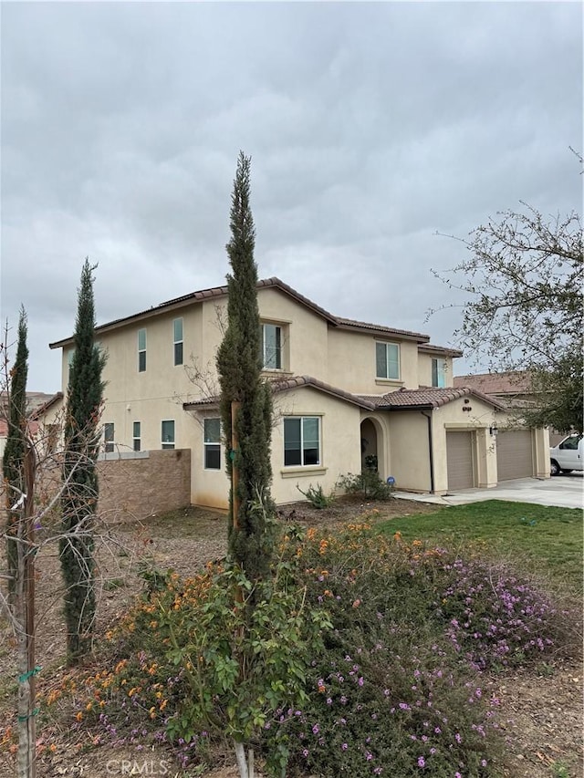 exterior space with stucco siding, a tile roof, fence, concrete driveway, and an attached garage