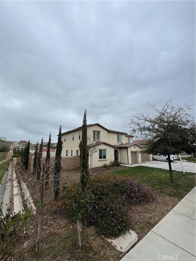 view of side of property with concrete driveway, a garage, and stucco siding