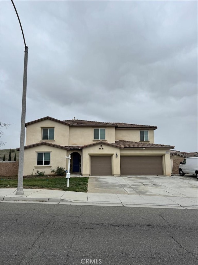 view of front of home featuring concrete driveway, a tiled roof, a garage, and stucco siding