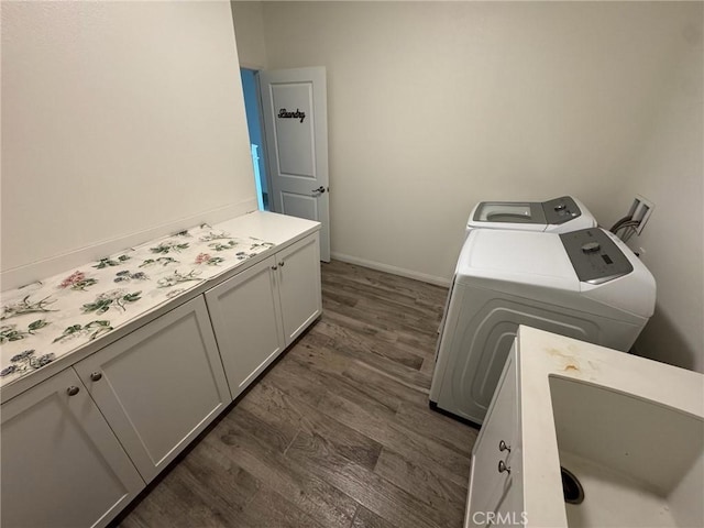 clothes washing area with baseboards, cabinet space, dark wood-style flooring, and washing machine and clothes dryer