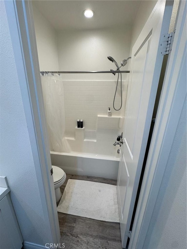 bathroom with toilet, wood finished floors, and shower / bath combo