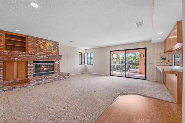 30220 Skippers Way Dr, Canyon Lake, CA 92587 - unfurnished living room with light colored carpet, visible vents, a brick fireplace, a textured ceiling, and baseboards