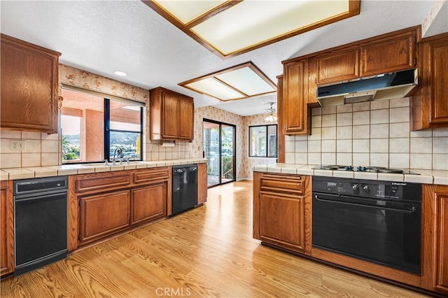 30220 Skippers Way Dr, Canyon Lake, CA 92587 - kitchen with tile countertops, under cabinet range hood, light wood-style floors, brown cabinets, and black appliances