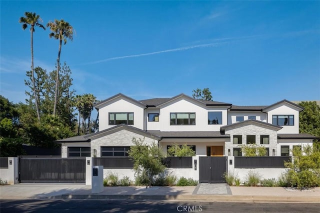 modern inspired farmhouse with a fenced front yard, a gate, stone siding, and concrete driveway