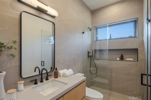 full bath featuring vanity, a shower stall, toilet, and tile walls