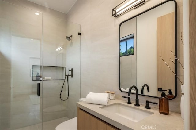 bathroom with toilet, a shower stall, tile walls, and vanity