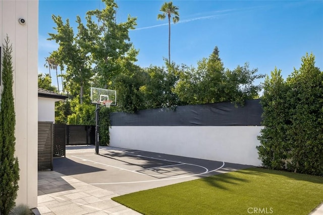 view of basketball court featuring community basketball court, fence, and a lawn