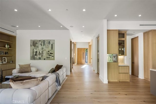 living area with baseboards, built in shelves, light wood-type flooring, and recessed lighting