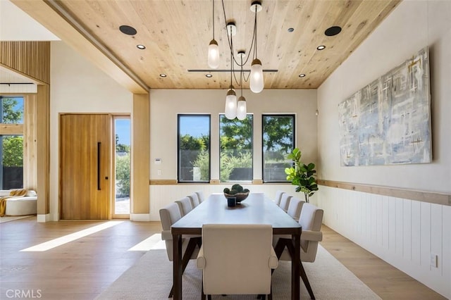 dining area with wooden ceiling, light wood-style flooring, plenty of natural light, and a wainscoted wall