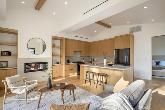 kitchen with a sink, visible vents, light countertops, black fridge, and range with gas cooktop