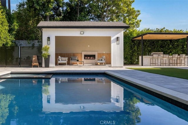 outdoor pool with an outbuilding, fence, an outdoor bar, a patio area, and an exterior structure