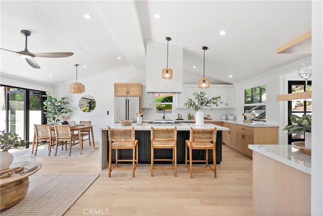 kitchen featuring a spacious island, stainless steel fridge, light brown cabinets, and light countertops