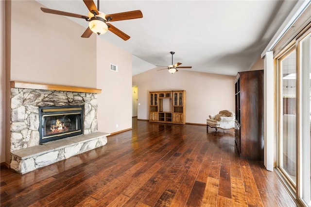 unfurnished living room featuring lofted ceiling, a stone fireplace, visible vents, baseboards, and dark wood finished floors