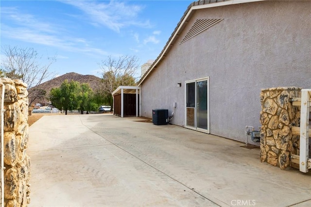 view of property exterior featuring a patio area, a mountain view, cooling unit, and stucco siding