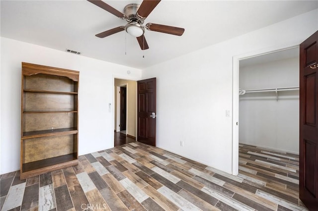 unfurnished bedroom with a closet, dark wood-style flooring, visible vents, and ceiling fan