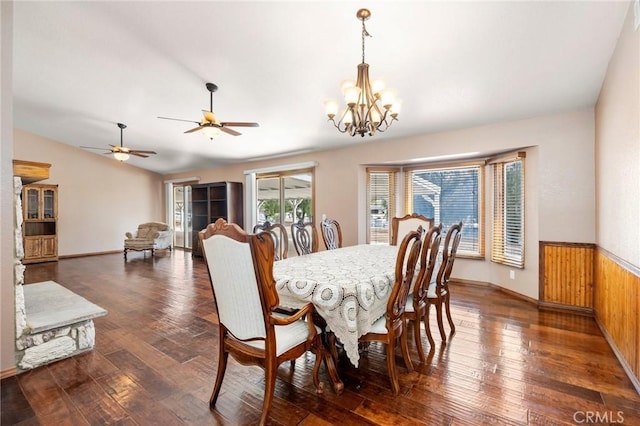 dining room featuring dark wood-style flooring, a notable chandelier, vaulted ceiling, and wainscoting