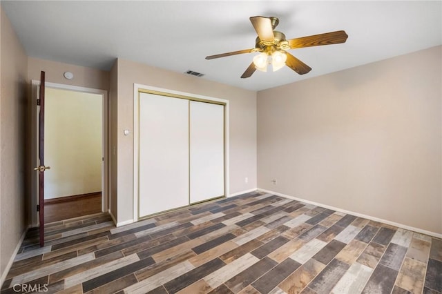 unfurnished bedroom with baseboards, visible vents, a ceiling fan, dark wood-style floors, and a closet