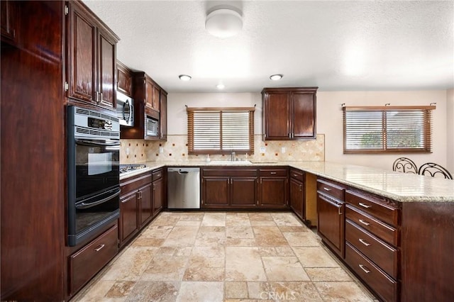 kitchen featuring a peninsula, a sink, appliances with stainless steel finishes, a warming drawer, and tasteful backsplash