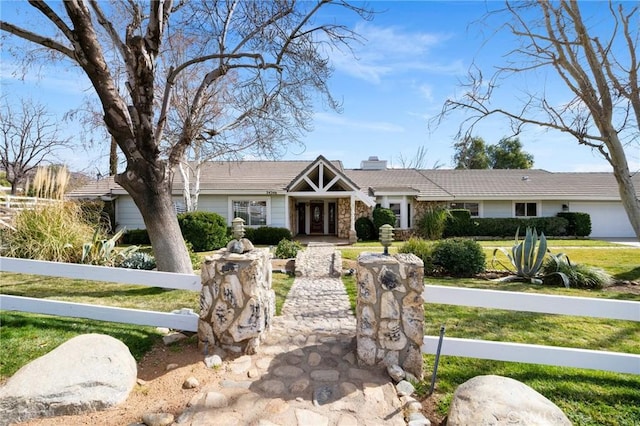 view of front facade with a fenced front yard, a front yard, stone siding, and a chimney