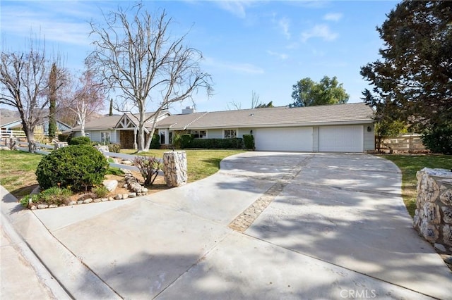 ranch-style home featuring a garage, concrete driveway, and a front lawn