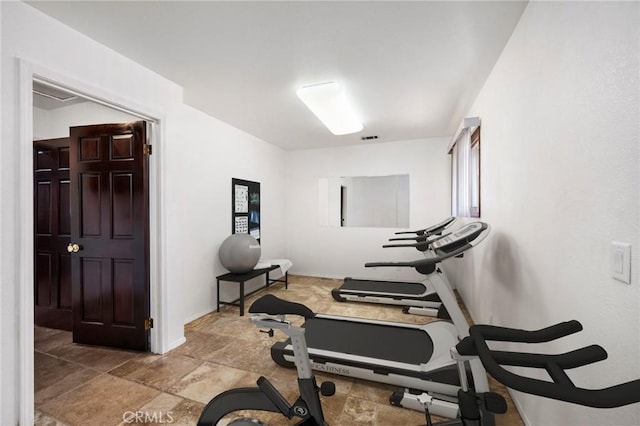 exercise room with stone finish floor, visible vents, and baseboards