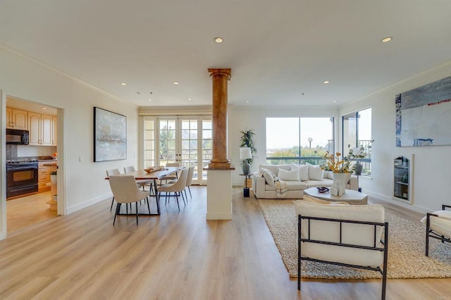 living area featuring crown molding, plenty of natural light, decorative columns, and light wood finished floors