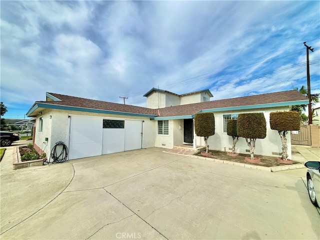 back of house featuring a garage, concrete driveway, and stucco siding