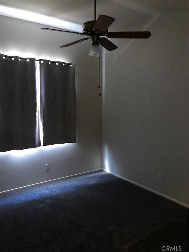 carpeted empty room featuring a ceiling fan and baseboards