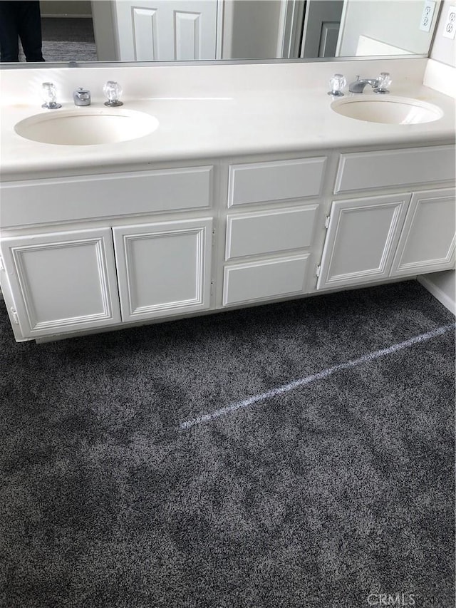 bathroom featuring double vanity, a sink, and carpet flooring