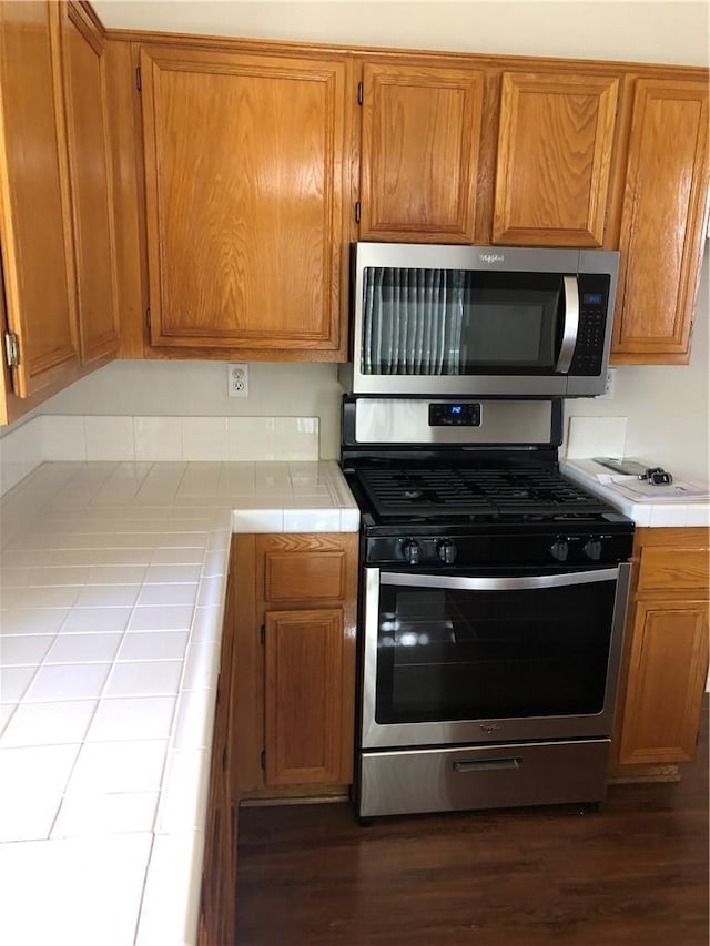 kitchen featuring appliances with stainless steel finishes, brown cabinetry, and tile counters