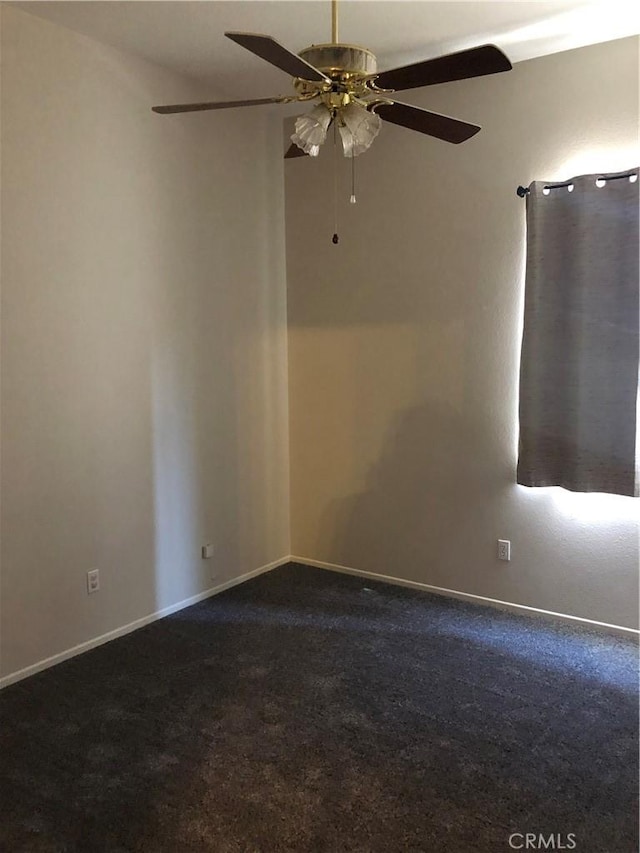 spare room featuring baseboards, dark carpet, and a ceiling fan