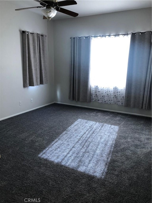 carpeted spare room with ceiling fan and baseboards