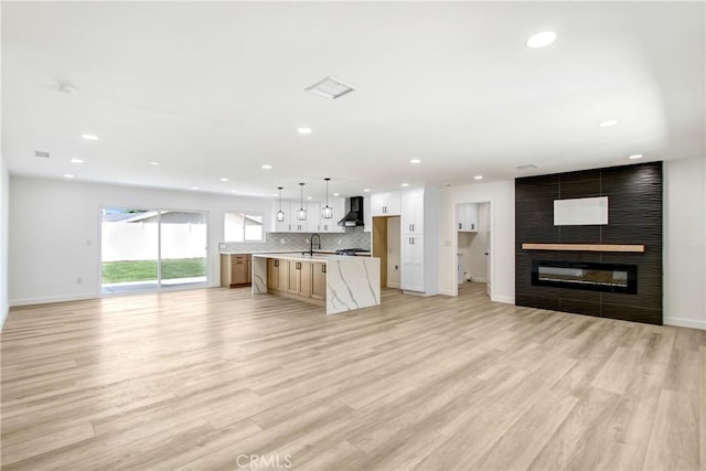 unfurnished living room featuring baseboards, light wood-type flooring, a fireplace, and recessed lighting