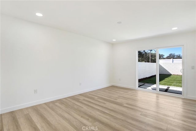 spare room featuring light wood finished floors, baseboards, and recessed lighting