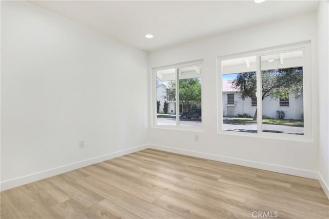 unfurnished room featuring light wood finished floors, baseboards, and recessed lighting