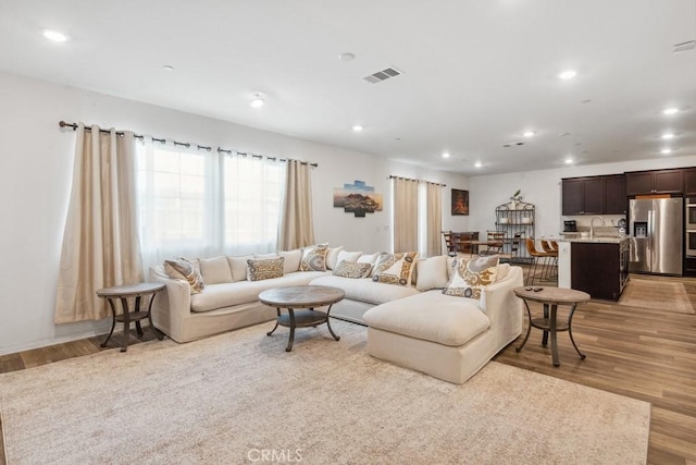 living area with recessed lighting, visible vents, and light wood finished floors