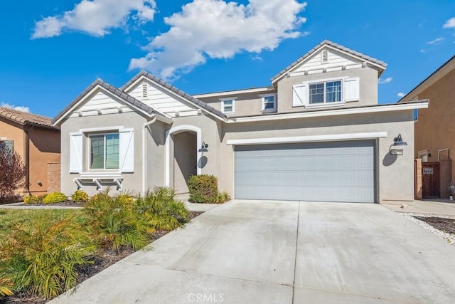 traditional-style house featuring a garage, concrete driveway, a tiled roof, and stucco siding