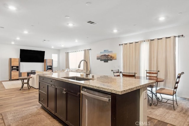 kitchen featuring a sink, visible vents, open floor plan, stainless steel dishwasher, and an island with sink