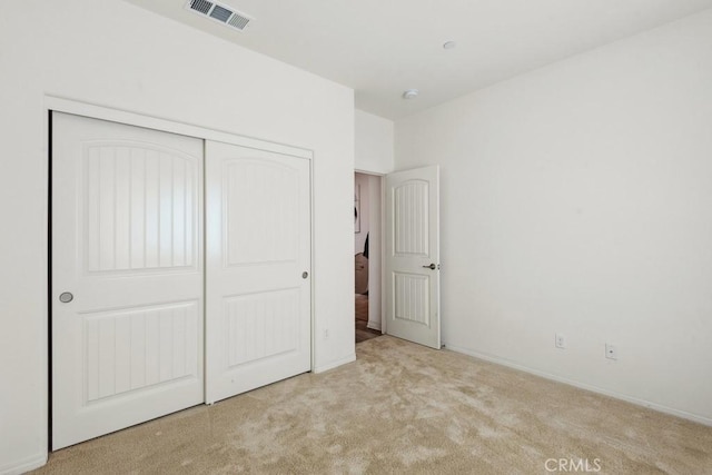 unfurnished bedroom featuring a closet, visible vents, and light carpet