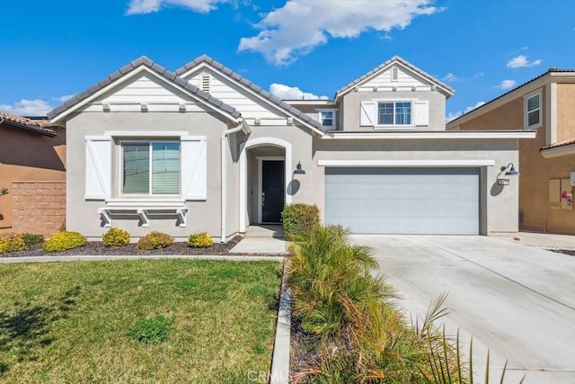 view of front of property featuring a garage, concrete driveway, a tiled roof, a front lawn, and stucco siding