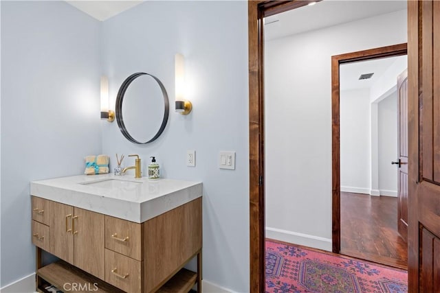 bathroom with baseboards, visible vents, wood finished floors, and vanity