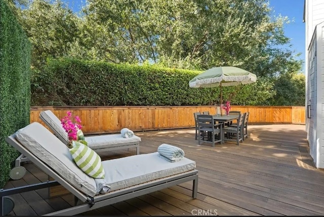 wooden deck with outdoor dining area and a fenced backyard