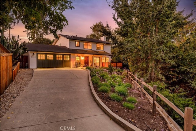 view of front of house with driveway, a garage, a chimney, and fence