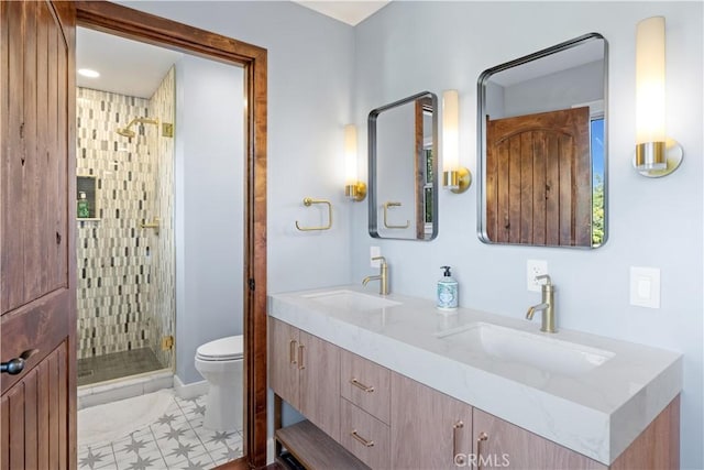 bathroom featuring double vanity, a stall shower, a sink, and toilet