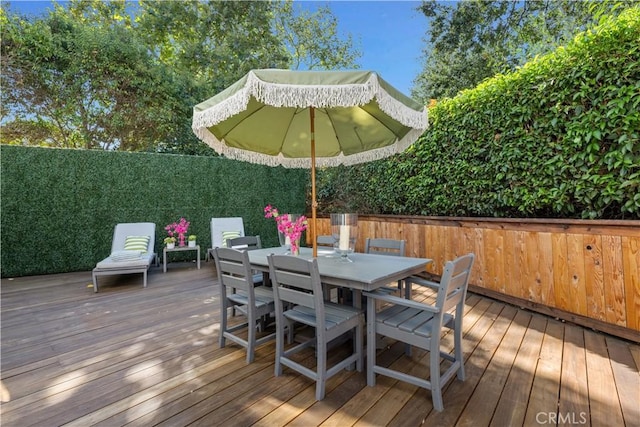 wooden deck with a fenced backyard and outdoor dining area