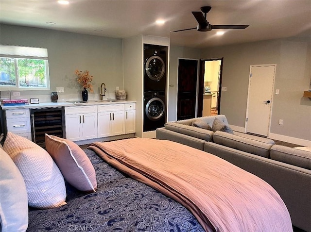 bedroom featuring wine cooler, stacked washer / dryer, a sink, baseboards, and indoor wet bar