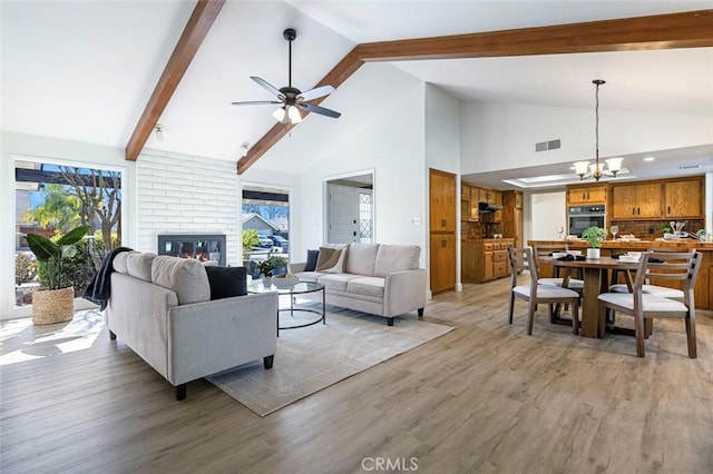 living area with a brick fireplace, light wood-style flooring, visible vents, and a wealth of natural light