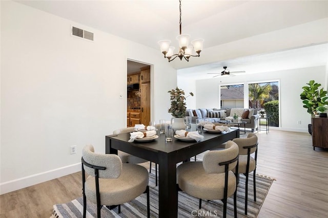 dining room with ceiling fan with notable chandelier, visible vents, baseboards, and wood finished floors